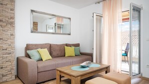 Een gezellige woonkamer met een bruine bank, een houten salontafel en een stenen muur.