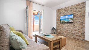 Een woonkamer met een houten tafel, een bank en een stenen muur met een televisie.