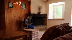Um quarto acolhedor com parede de madeira, lareira, janela e uma pessoa lendo.