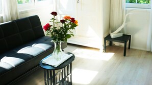 A room with a black sofa, a small table with a vase of flowers, a white cabinet, and a chair. - Vacation house BLACK & WHITE (Bromberg)