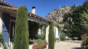 Un espace extérieur abrité, doté d’un chemin de gravier, de plantes en pot et d’une structure en forme de pergola.