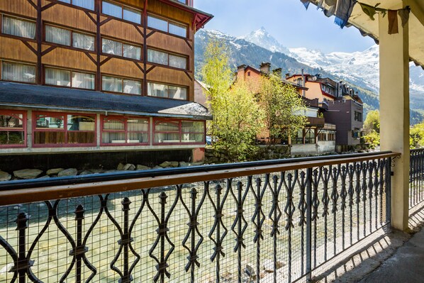 A hotel with a wooden facade, a balcony with a wrought iron railing, and a view of snow-capped mountains in the background.