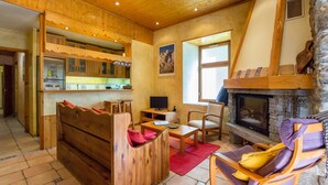 A cozy wooden interior with a fireplace, wooden furniture, and a stone wall. - Chamonix centre 2BR - Fireplace, stone walls, balcony with View of Mont Blanc (Chamonix-Mont-Blanc)