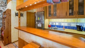 A kitchen with wooden cabinets, a stainless steel refrigerator, and a tiled backsplash. - Chamonix centre 2BR - Fireplace, stone walls, balcony with View of Mont Blanc (Chamonix-Mont-Blanc)
