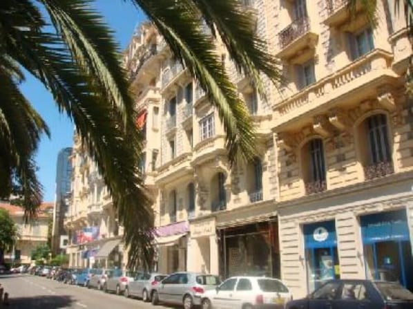 A street lined with historic buildings, parked cars, and palm trees.