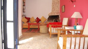 Un accogliente soggiorno con camino in mattoni, un divano con cuscini, un tavolo di legno e una poltrona.