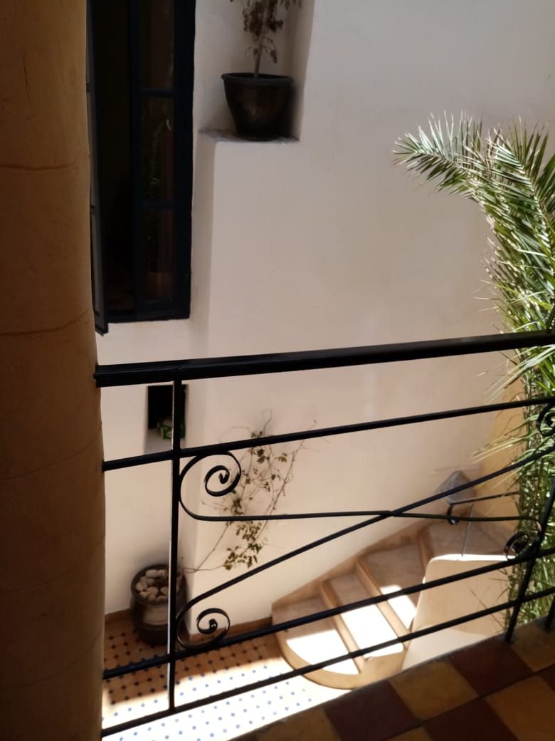 Ein Balkon mit Metallgeländer, einem Blumentopf und einem gefliesten Boden.