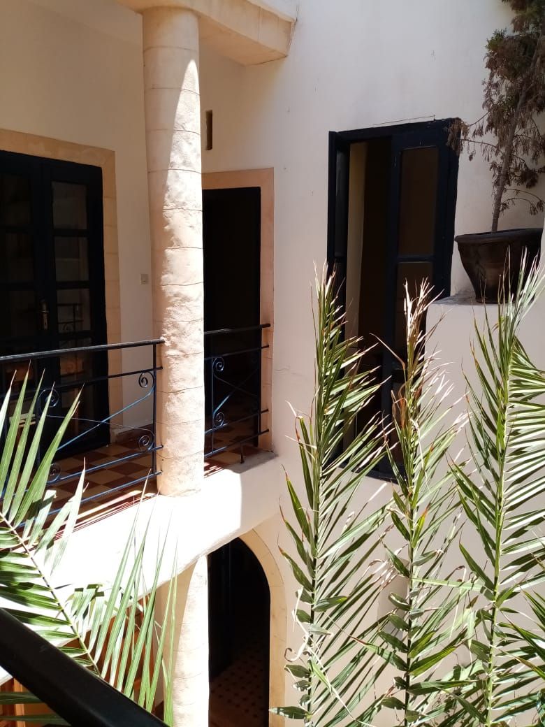 Une cour intérieure agrémentée d’une colonne, d’une balustrade et de plantes en pot.