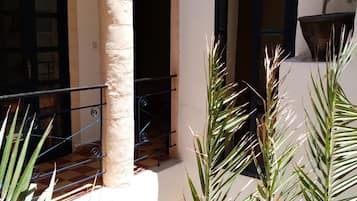 Une cour intérieure agrémentée d’une colonne, d’une balustrade et de plantes en pot.