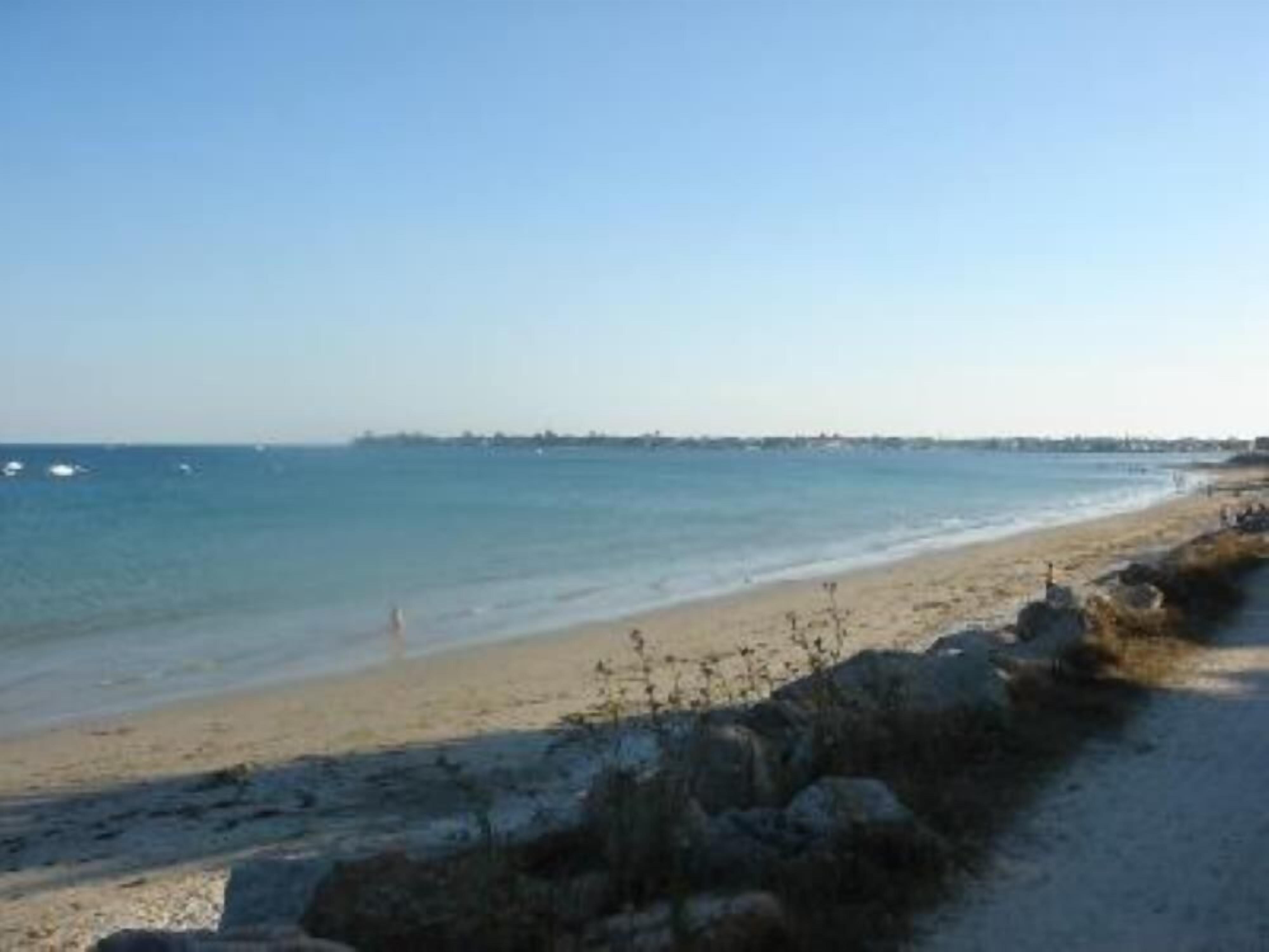 Een strand met een rotsachtige kustlijn en een rustige zee.