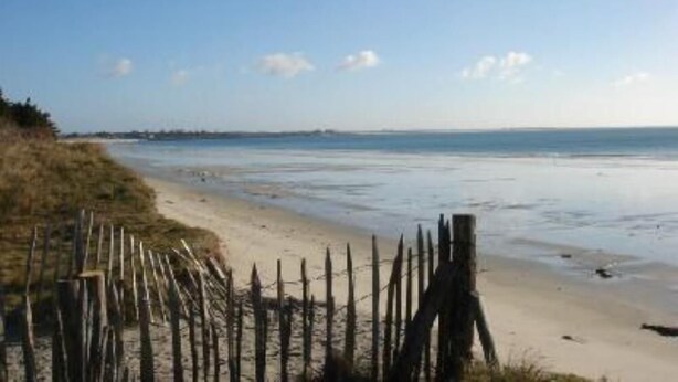 Ein Strand mit einer Holzlattenveranda und blauem Himmel.