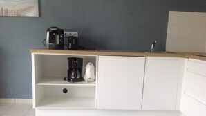 Eine Küche mit weißen Schränken, einer Holzausziehtheke und einer Kaffeemaschine.
