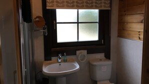 A small bathroom with a window, a sink, and a toilet. - Cherry Lodge, Cedar Springs, Self Catering Log Cabin, Heacham,Close to the Beach (King's Lynn)