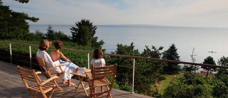 A wooden deck with outdoor seating overlooking a body of water.