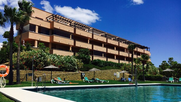 Un hotel con piscina, varios pisos y zonas de estar al aire libre.