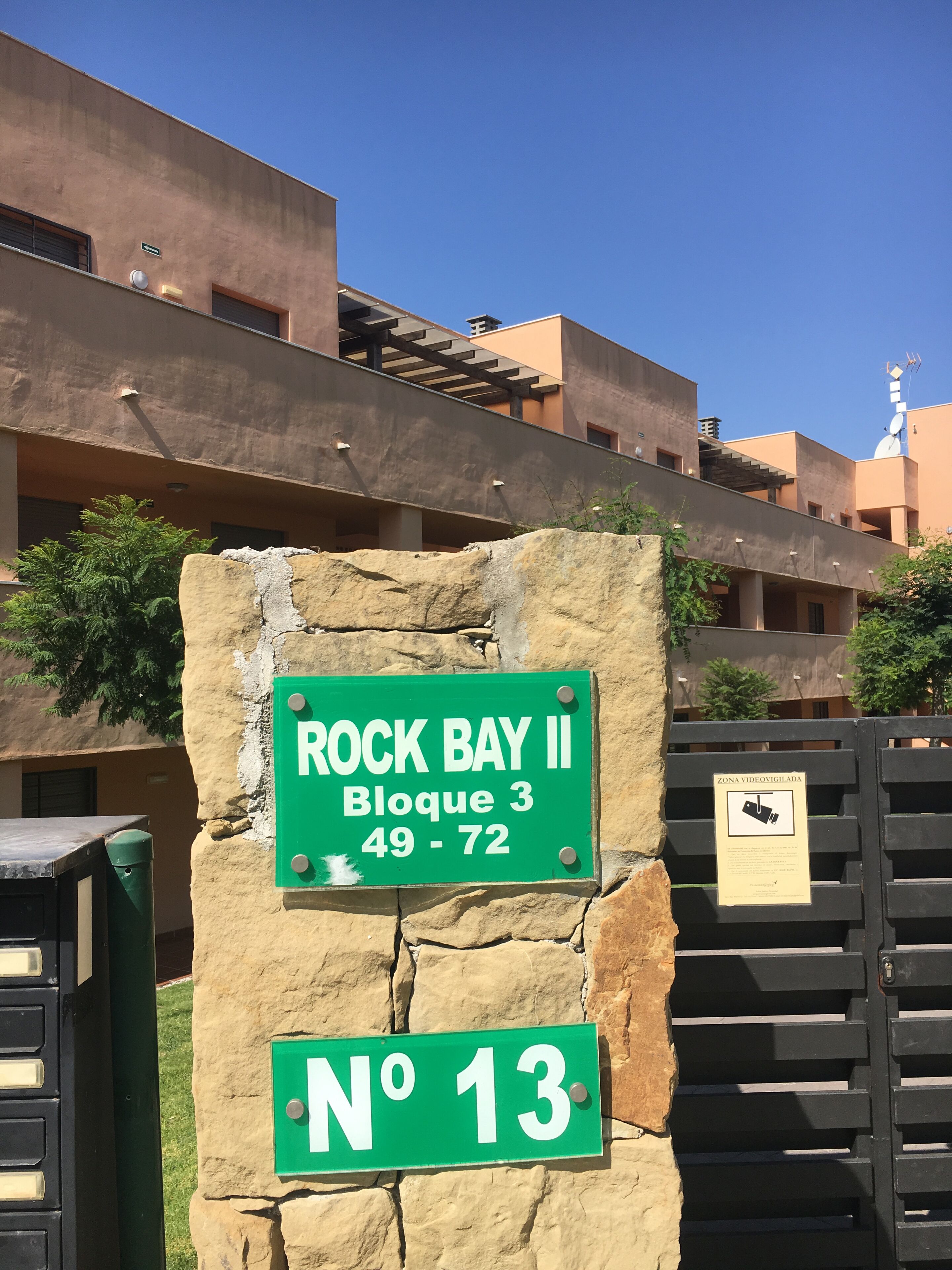 Un segnale che indica 'ROCK BAY II Block 3 49-72' e 'No 13' su un muro di pietra.