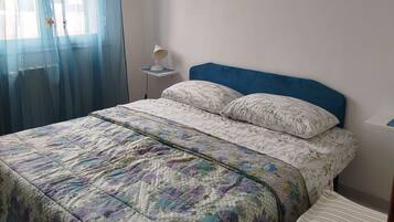 Une chambre à coucher avec un lit, une table de chevet, une chaise, une lampe suspendue et un tableau au mur.