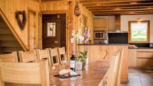 Een houten interieur met een eettafel voor twee personen, een keuken met moderne apparaten, en een houten stoel in de vorm van een hart.