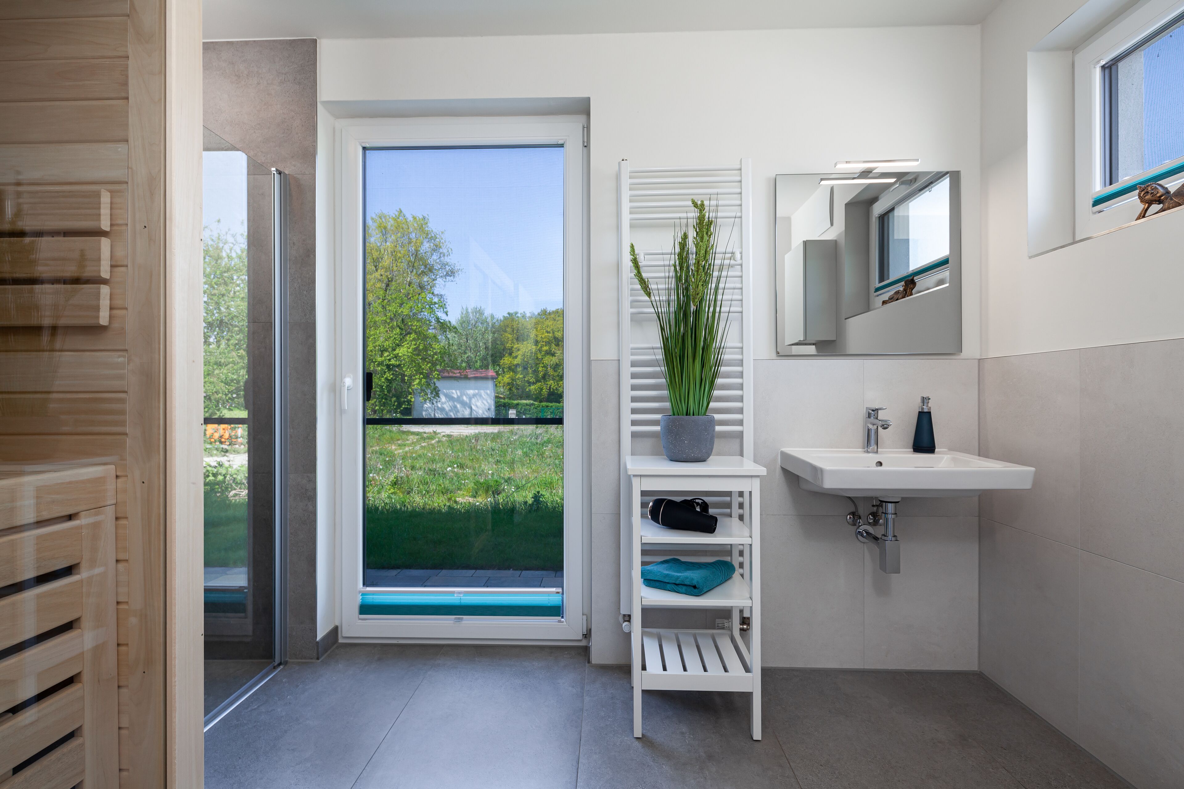 Un bagno moderno con un lavandino bianco, uno specchio e una pianta in vaso.