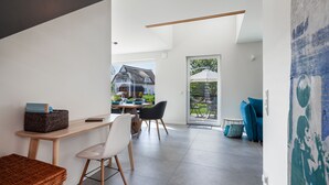 Un interior moderno con comedor, un banco de mimbre y vistas al exterior.