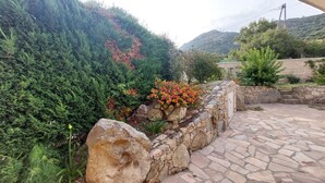 Un camí de pedra que condueix a una paret de pedra amb un jardí de flors.