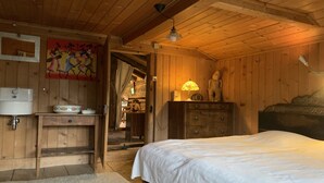 A wooden room with a bed, a dresser, a lamp, and a painting on the wall. - authentic luxury chalet with garden (La Forclaz)