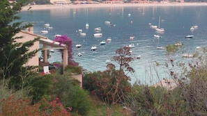 Une vue sur la côte, avec des bateaux sur l’eau, un bâtiment doté d’une pergola et une plage en arrière-plan.