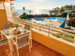 A balcony with a table set for breakfast, overlooking a swimming pool and the sea. - Apartment on the beachfront, front sea view, swimming pools, tennis (Calpe)