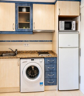A compact kitchen with a washing machine, a microwave, and a refrigerator. - Apartment on the beachfront, front sea view, swimming pools, tennis (Calpe)