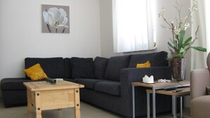 A modern living room with a dark grey sectional sofa, a wooden coffee table, a glass side table, and a potted plant. - Luxury vacation home for summer with private pool and winter at the slopes (Annaberg)