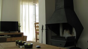 A living room with a TV, a fireplace, and a dining table with candles. - Luxury vacation home for summer with private pool and winter at the slopes (Annaberg)