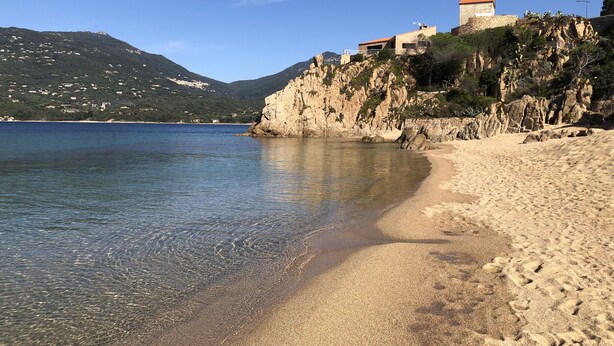 A coastal beach with clear water, sandy shore, and buildings on a rocky cliff. - Apartment/ flat - PROPRIANO (Propriano)