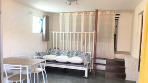 A room with a white sofa, a wooden table, and chairs. There is a staircase leading to another level. - Apartment/ flat - PROPRIANO (Propriano)