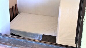 A small, enclosed room with a single bed, a wooden headboard, and a plain white wall. - Apartment/ flat - PROPRIANO (Propriano)