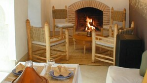 Una habitación acogedora con chimenea, muebles de madera y una mesa con una botella y copas.