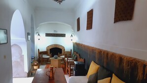 Un salón acogedor con una mesa de madera, un sofá con cojines, una chimenea y una vista a través de un arco.