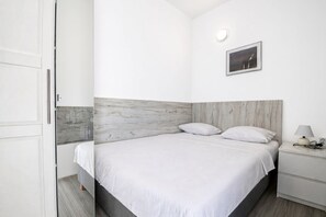 A bedroom with a bed, bedside table, and a wall-mounted light fixture. - Apartment with 2 bedrooms, terrace with sea view, right on the beach (Betina)