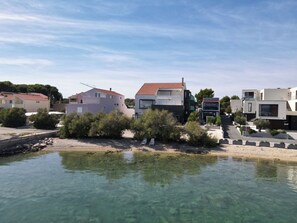 A coastal residential area with houses, a clear water body, and a sandy beach. - Apartment with 2 bedrooms, terrace with sea view, right on the beach (Betina)