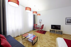 Un salon moderne comprenant un canapé, une table basse, un téléviseur et un coin repas avec des chaises et une table.