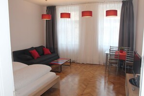 Une chambre moderne équipée d’un canapé, d’une petite table, d’un téléviseur et d’un coin repas.