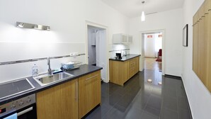 Eine moderne Küche mit schwarzem Arbeitsplatz, Spüle aus Edelstahl, Holzschränken und einem eingebauten Backofen.