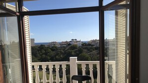 A balcony with a white balustrade, a chair with an orange cushion, and a view of houses and greenery. - Hillside / sea giant pool Alicante-Torrevieja-La Mata (Torrevieja)
