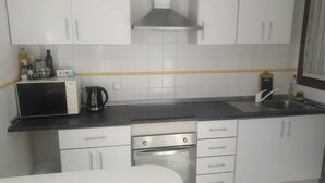 A modern kitchen with white cabinets, a black countertop, a stainless steel range hood, a microwave, a coffee maker, and a sink. - Hillside / sea giant pool Alicante-Torrevieja-La Mata (Torrevieja)