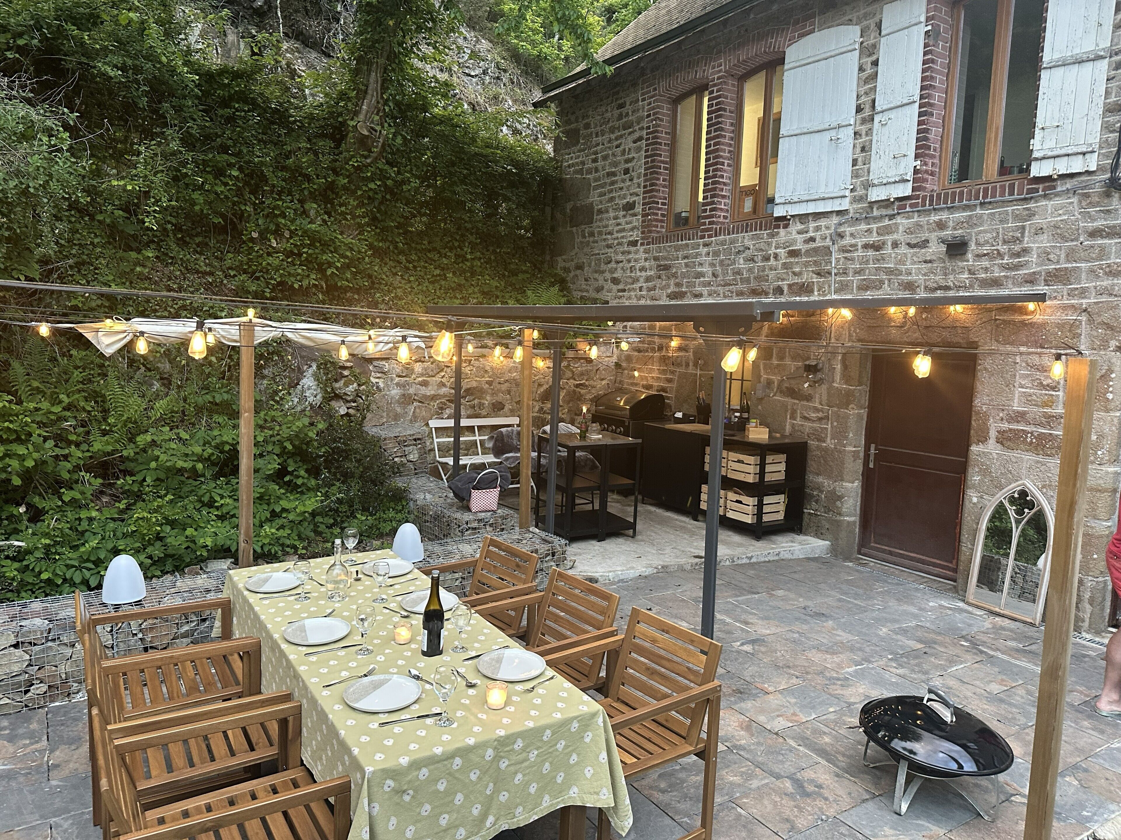 Une terrasse extérieure avec une table à manger pour quatre personnes, entourée de chaises en bois.