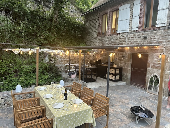 An outdoor patio with a dining table set for four, surrounded by wooden chairs.