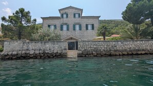 A stone building with a central entrance, surrounded by a stone wall and water.