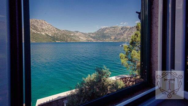 A view of a lake with mountains in the background, a clear sky, and a window frame.