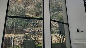 A modern interior with large glass windows offering views of a garden and trees. - South facing Villa with Panoramic Sea View, POOL, AC, Quiet  (Grasse)