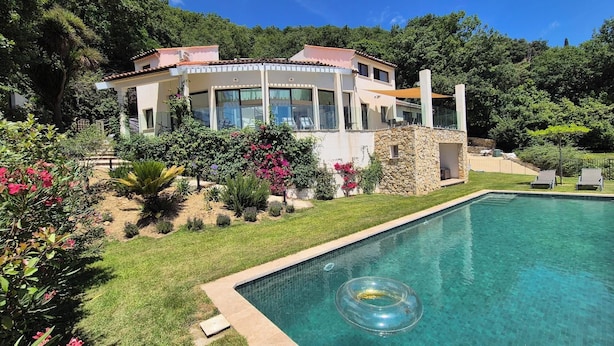 A modern house with a swimming pool, surrounded by lush greenery and a stone structure. - South facing Villa with Panoramic Sea View, POOL, AC, Quiet  (Grasse)