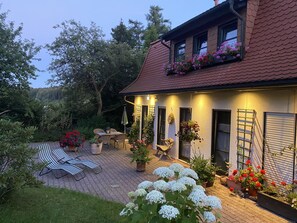 A house with a tiled roof, a brick patio, outdoor furniture, and potted plants.